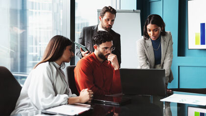 Businesspeople collaborating around laptop in an office