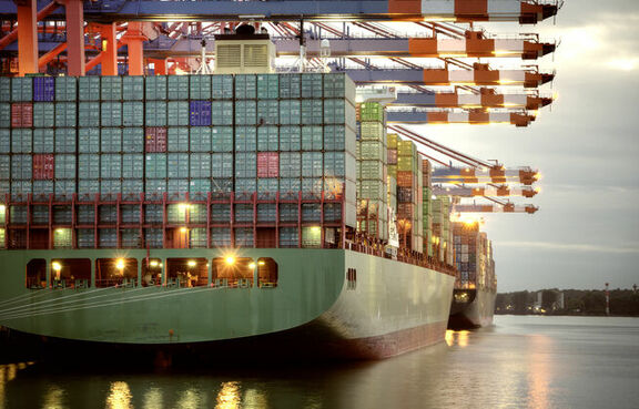 Cargo ship under container cranes at dusk