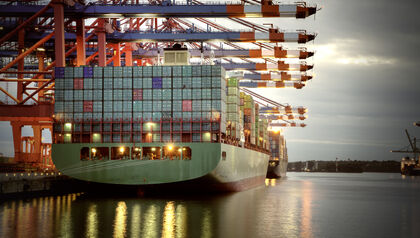 Cargo ship under container cranes at dusk