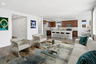 open-concept space with a large white couch, a glass coffee table, and royal green accent pillows