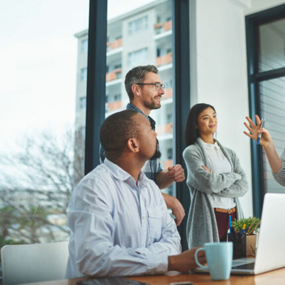 Random group of coworkers in a discussion in an office with a large window