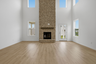 great room with two-story stone fireplace, wood floors, and large windows