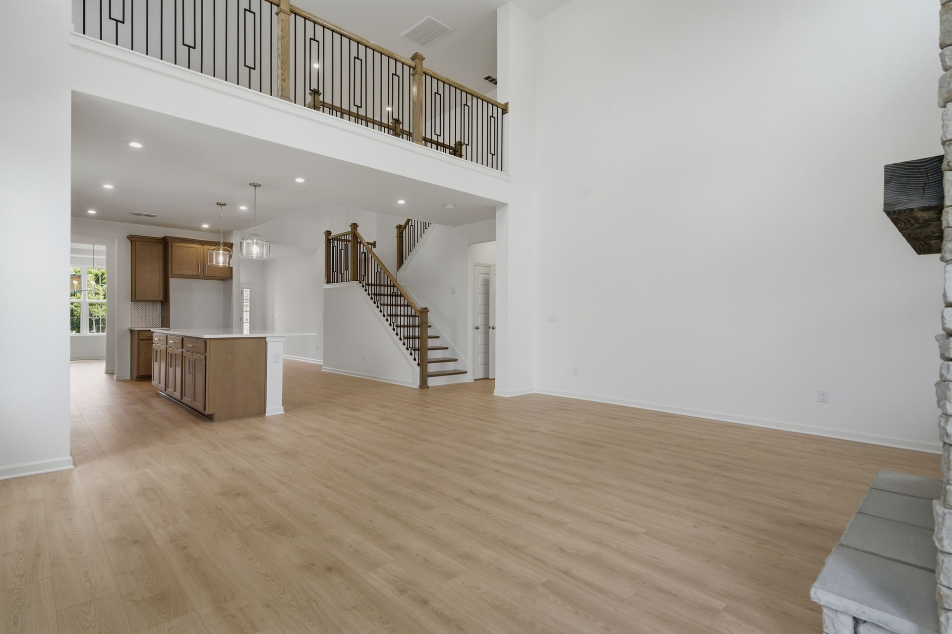 great room with two-story stone fireplace, wood floors, and large windows