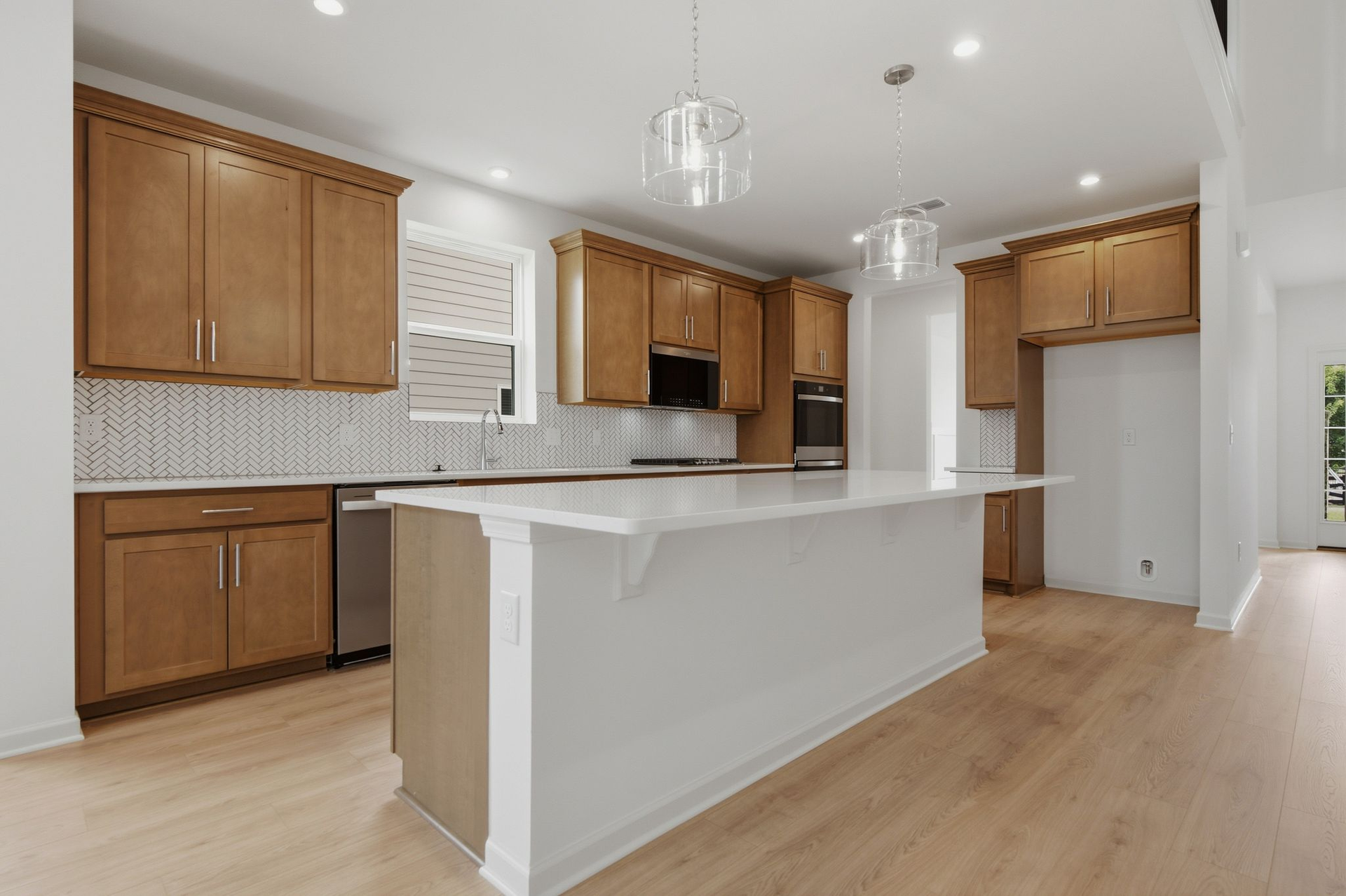 kitchen with wood cabinets, white countertops, large island with accent lighting, built in microwave and oven, and stainless steel appliances