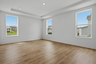 primary bedroom with wood floors, large windows, white walls, and tray ceiling