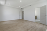 primary bedroom with wood floors, large windows, white walls, and tray ceiling