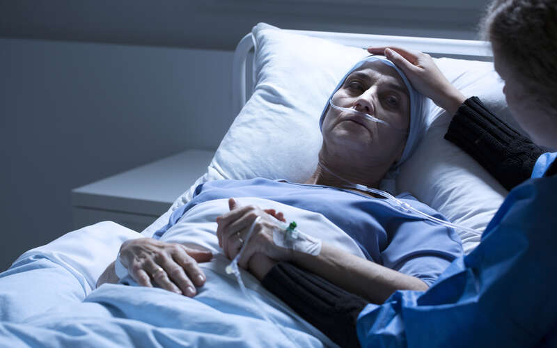 image of women in hospital bed being comforted by another