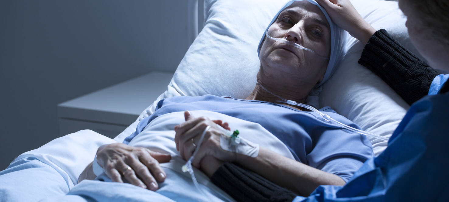 image of women in hospital bed being comforted by another