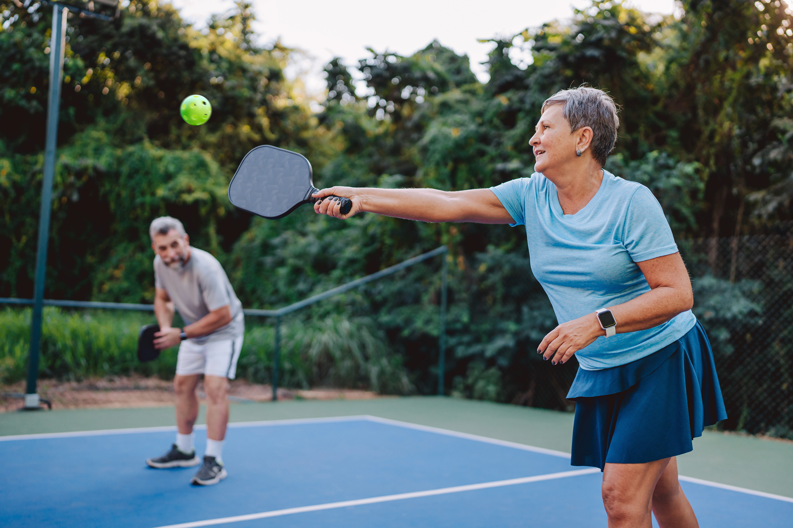 man and woman playing pickleball on court