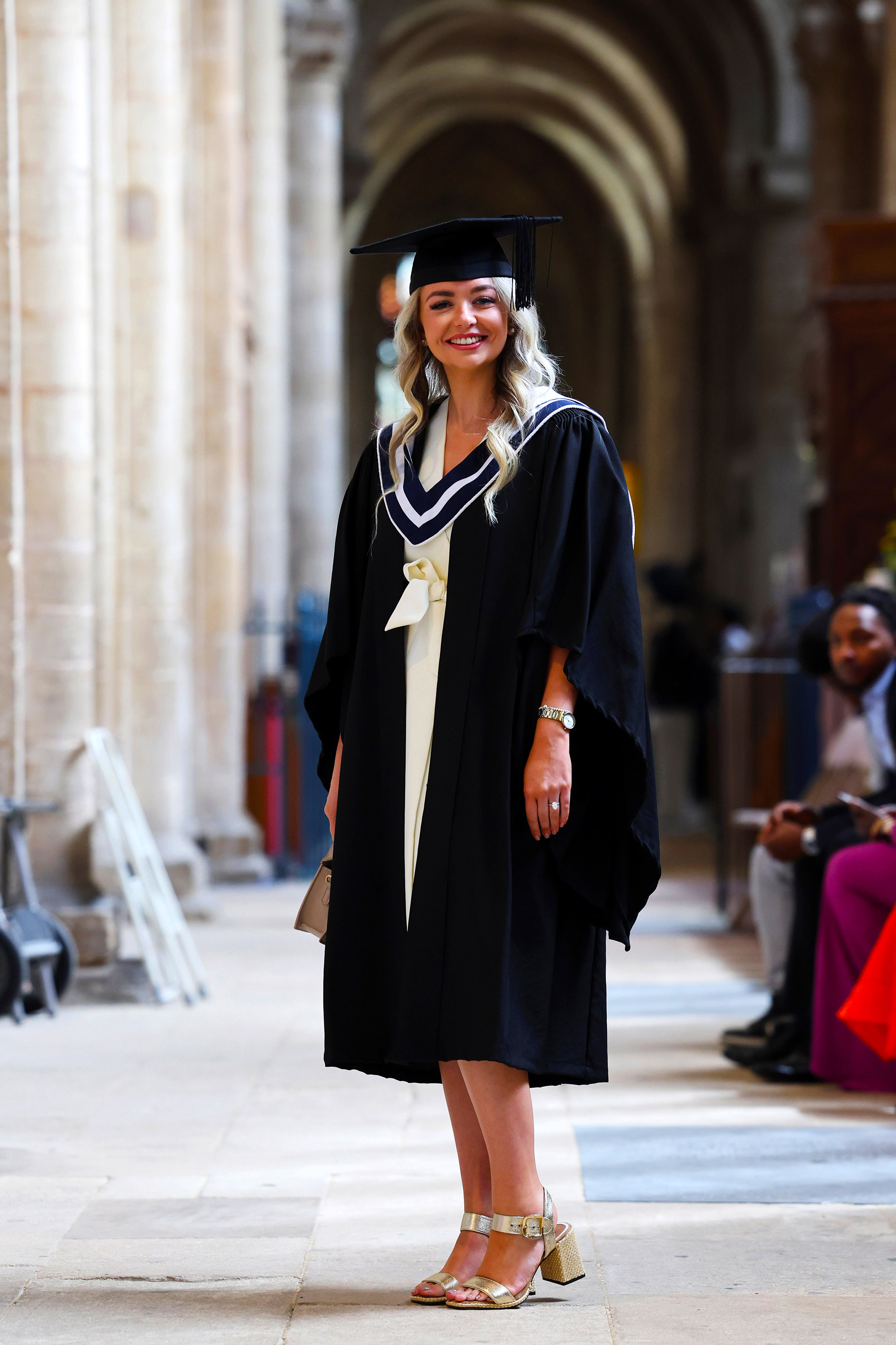 Full-length photo of a female graduate standing and smiling in the aisle