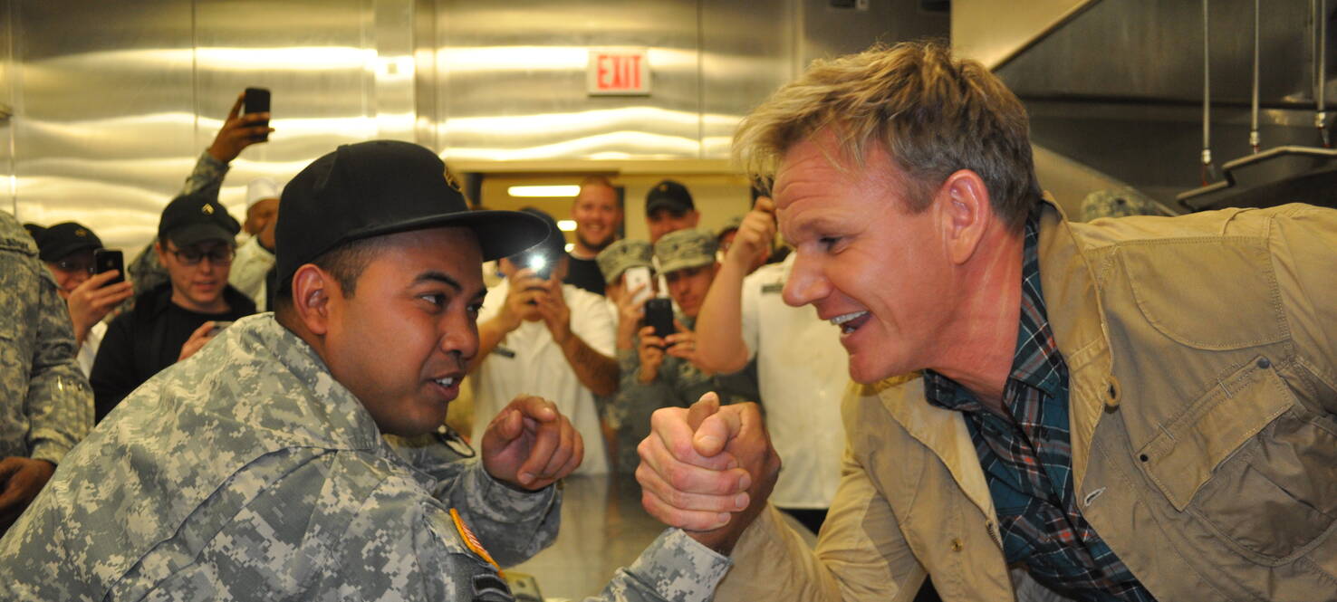 Celebrity chef Gordon Ramsey, right, arm wrestles with a member of the US Army.