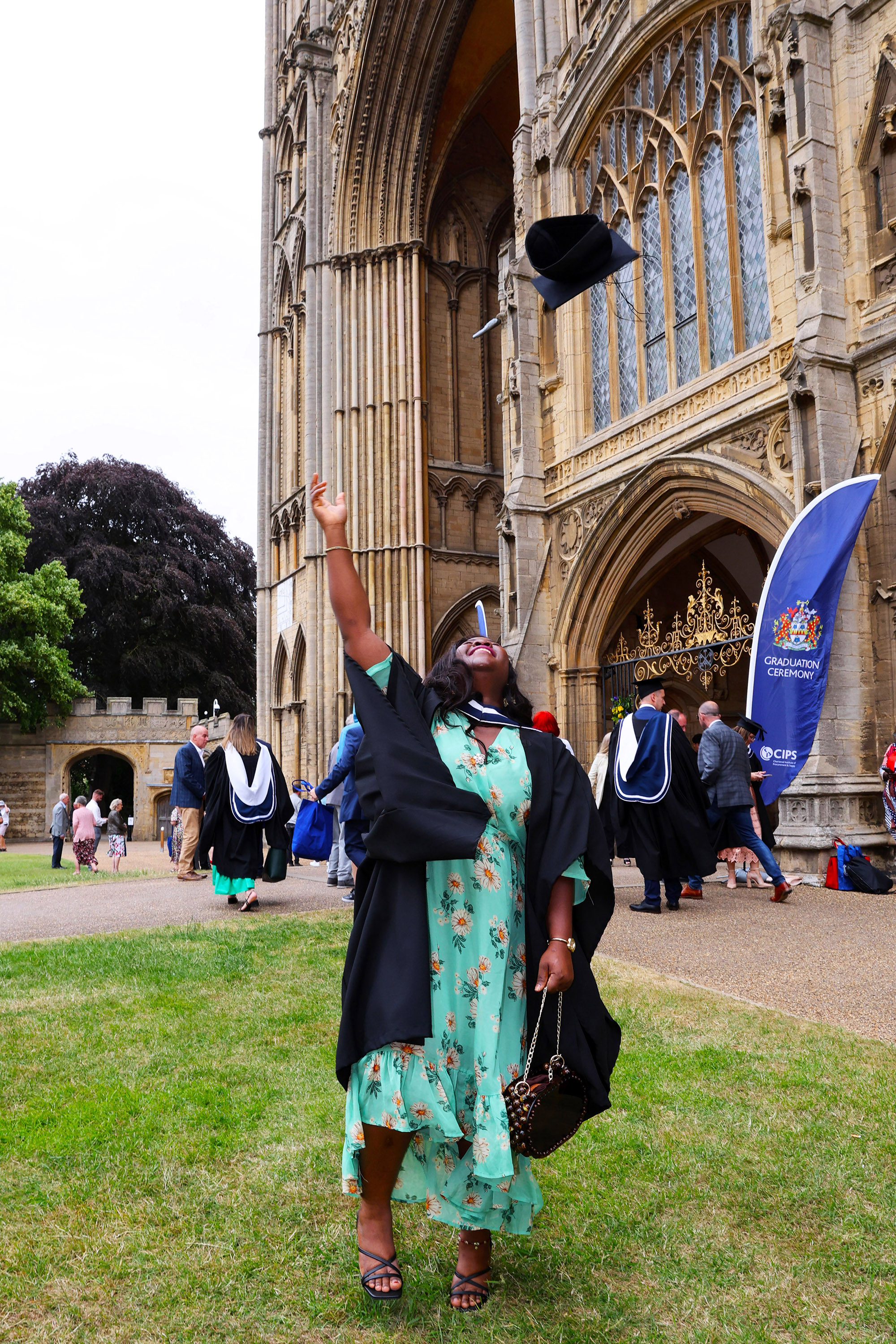 Graduate throwing her cap in the air outside the building