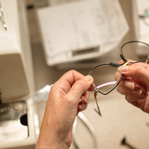Optician holding pair of glasses