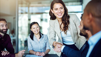 Young woman shaking hands with male co-worker in an office
