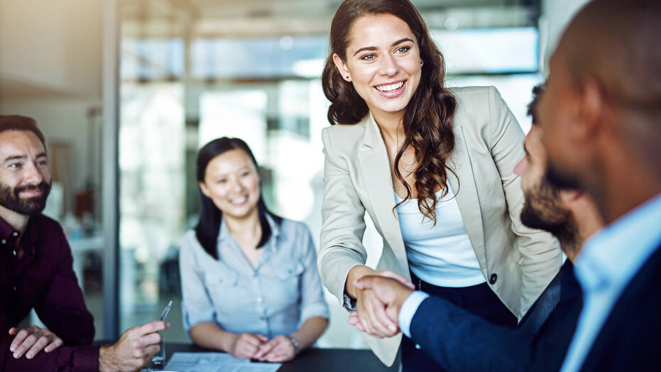 Young woman shaking hands with male co-worker in an office
