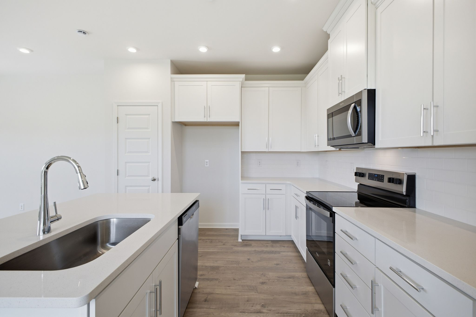kitchen with white cabinets and counters, wood floors, and stainless steel appliances