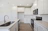 kitchen with white cabinets and counters, wood floors, and stainless steel appliances