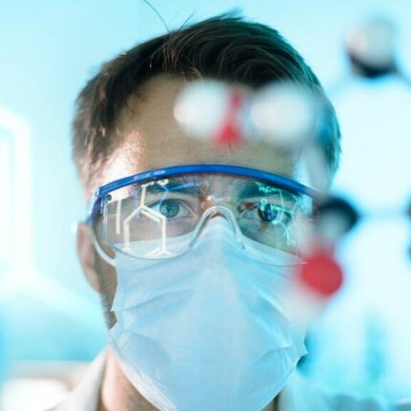 Scientist in a lab with goggles and face mask
