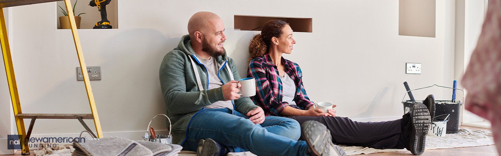 A man and woman sitting on the floor relaxing during a home renovation.