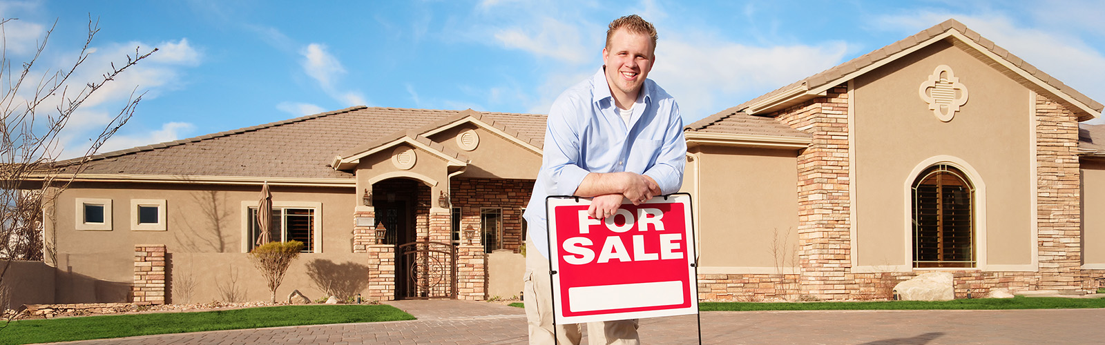 Man standing by a for sale sign in front of a house