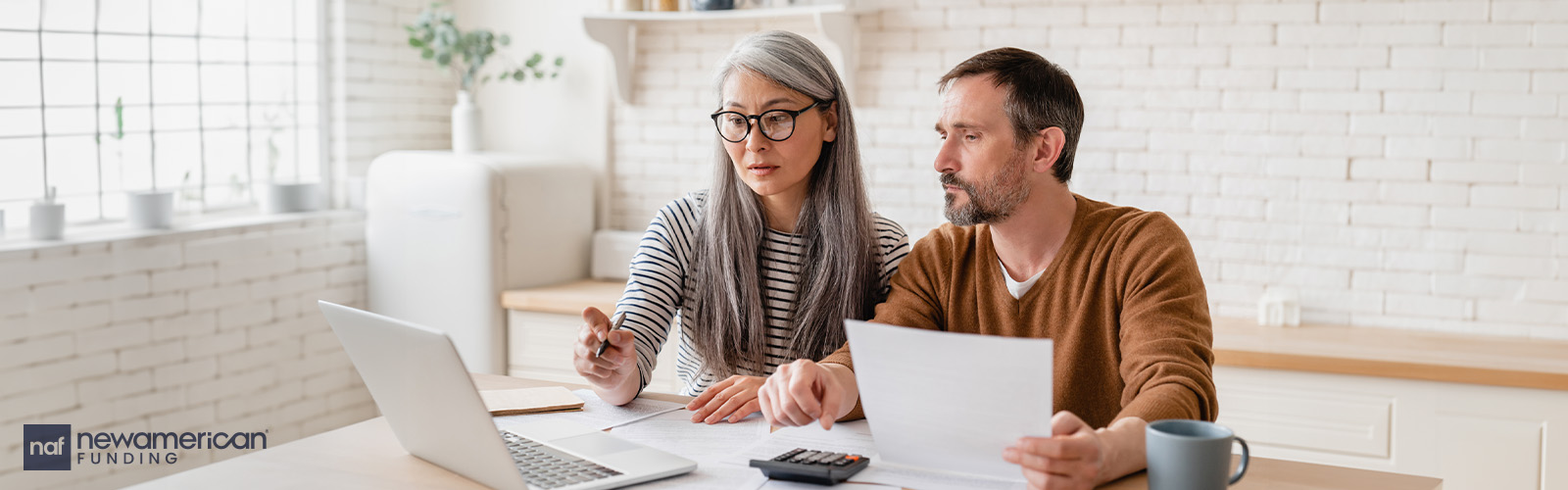 Woman and man looking at documents and laptop computer