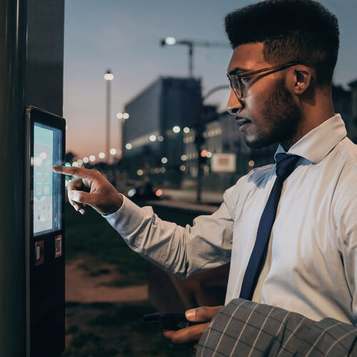 Man wearing glasses and a tie rings doorbell at night time