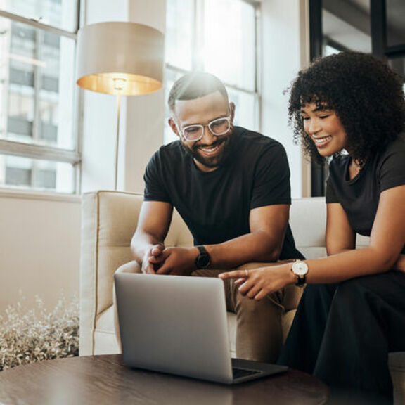 Young black couple on sofa with laptop