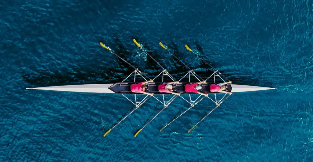 A birdseye view of a rowing team of four in a boat wearing pink tops