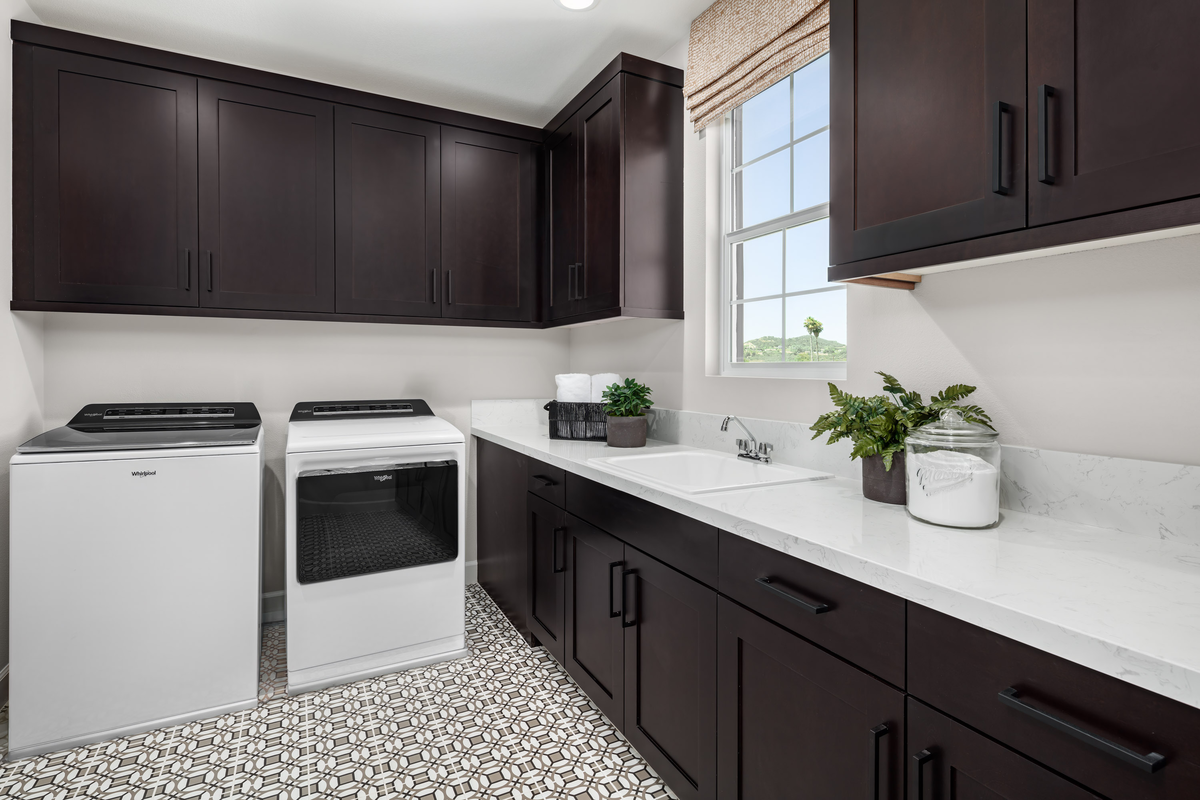 laundry room with tiled floors and dark cabinets
