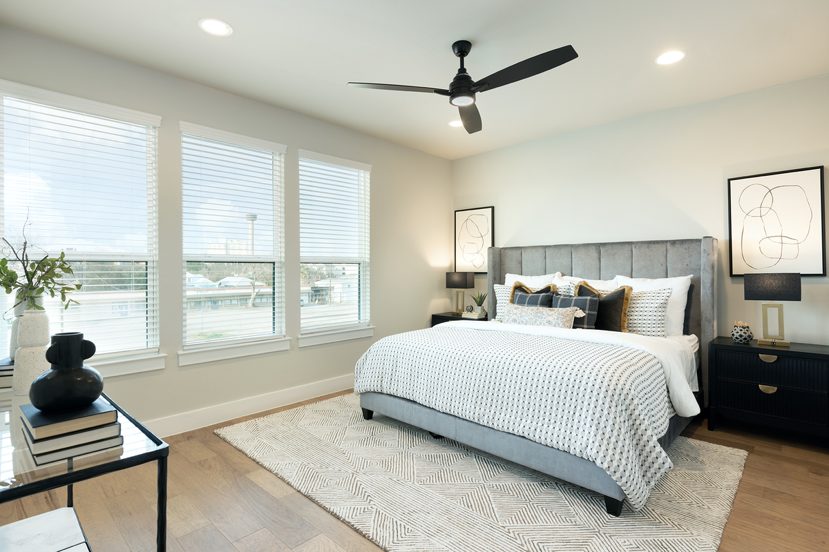 bedroom with brown flooring, rug & windows 