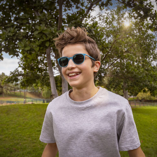 Boy in grey t-shirt standing outside while wearing HOYA MiYOSMART glasses
