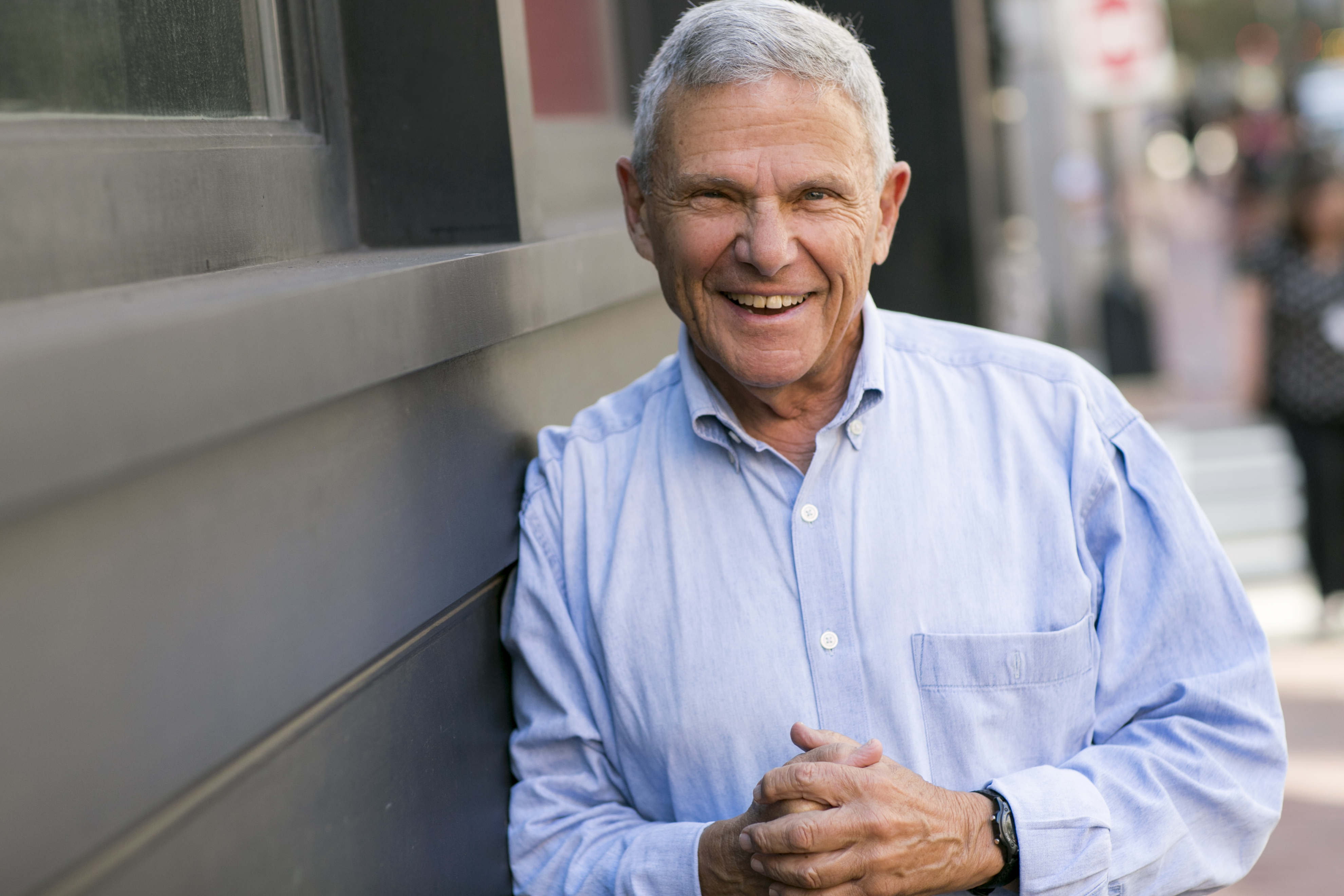 Mike Zoob smiles at the camera while leaning against a building