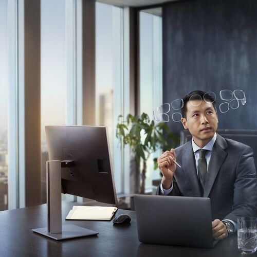 Man in suit behind desk, wearing HOYA MySelf Profile glasses with a halo of lenses around his head