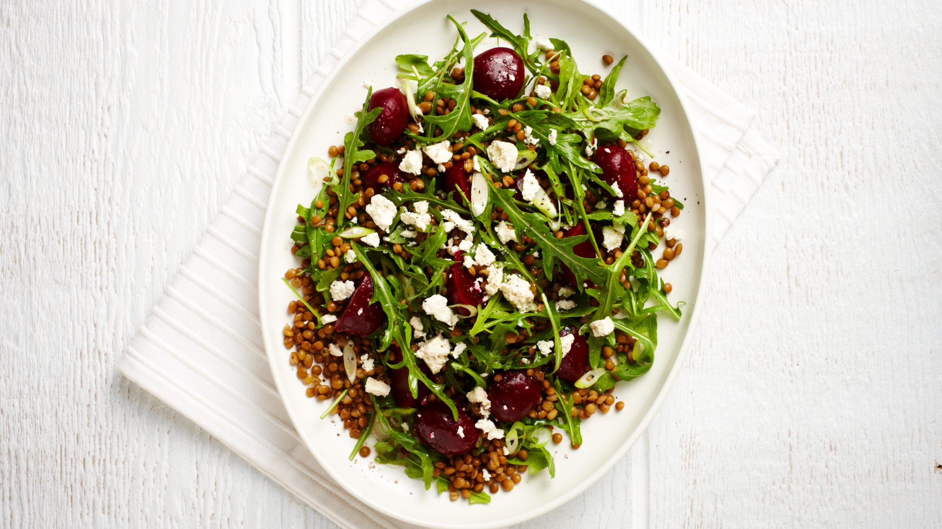 Nutrition Australia's Beetroot, Lentil and Feta Salad served on a white plate, placed on a white table.