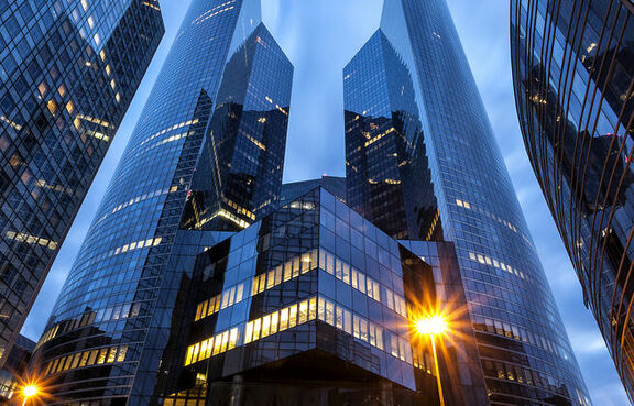 Tall glass buildings at dusk in front of a cloudy sky