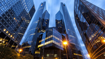 Tall glass buildings at dusk in front of a cloudy sky