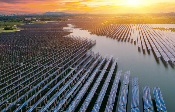 aerial photo of a field filled with solar panels and a creek running through the middle of it