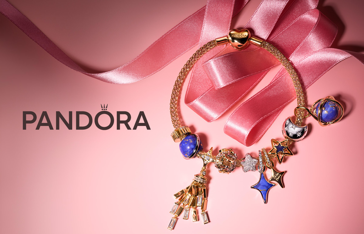 image of pandora bracelet sitting on pink background with pink ribbon around it