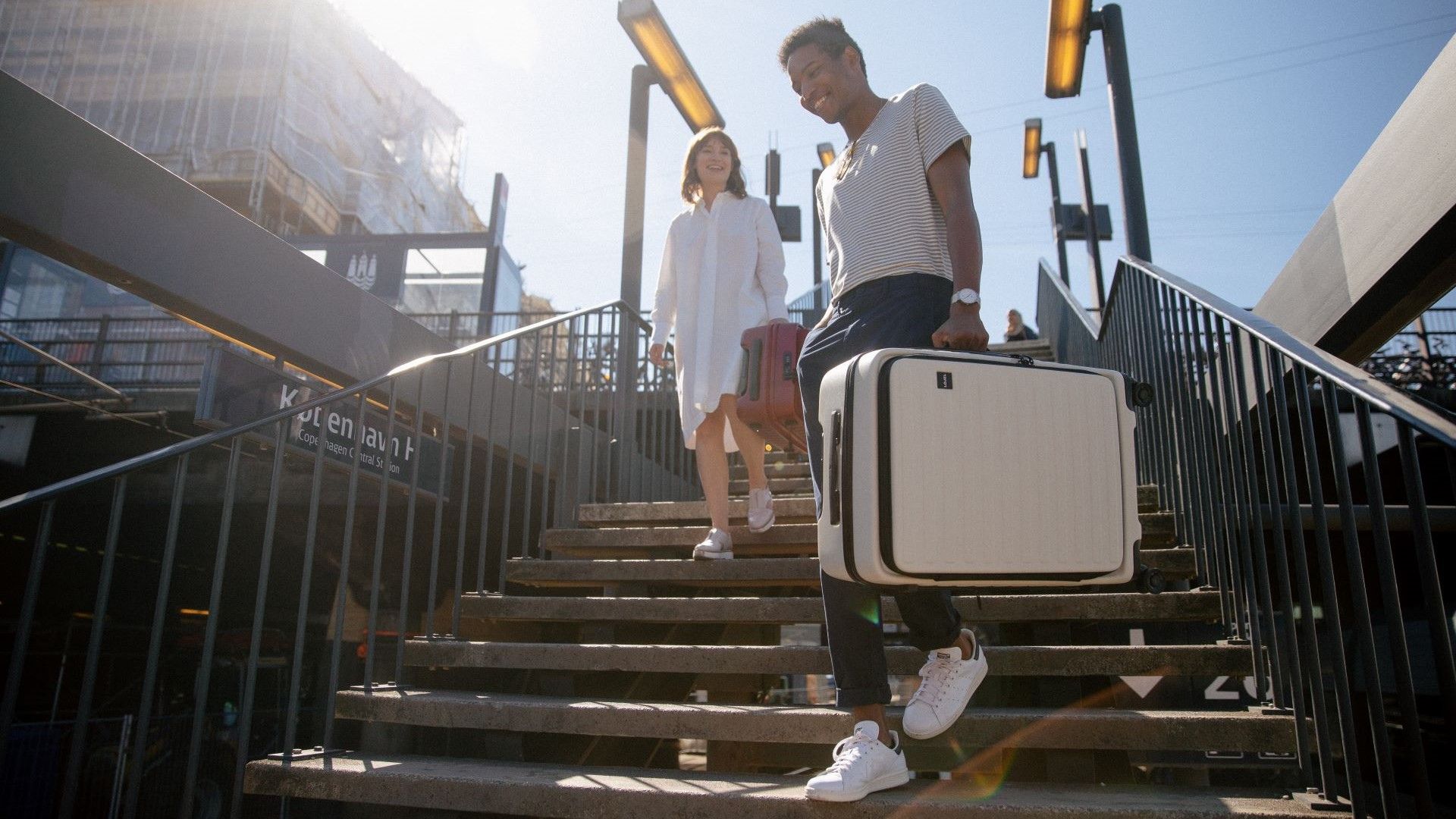 man and women walking down train station stairs with luggage in hand