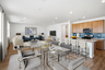 open-concept space with a glass dining table, grey chairs, and grey rug