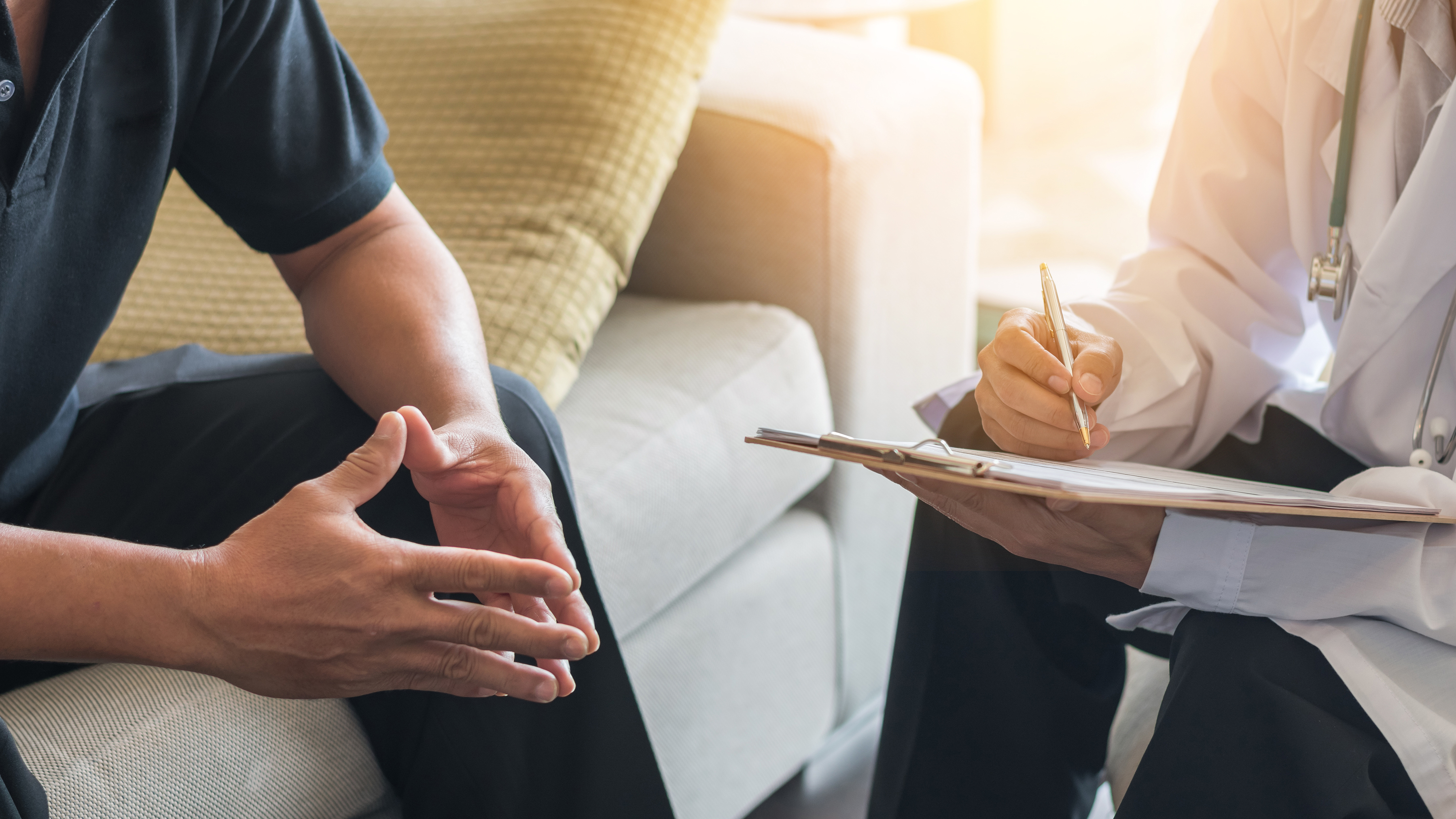 a man sitting on a couch across from a doctor holding a chart