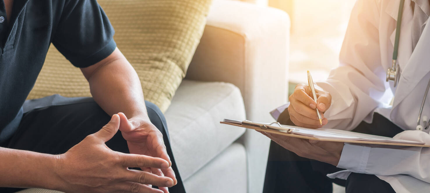 a man sitting on a couch across from a doctor holding a chart