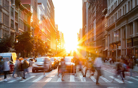 Pedestrians in a crosswalk in a city at sunrise 