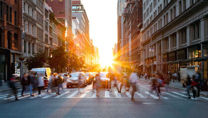 Pedestrians in a crosswalk in a city at sunrise 