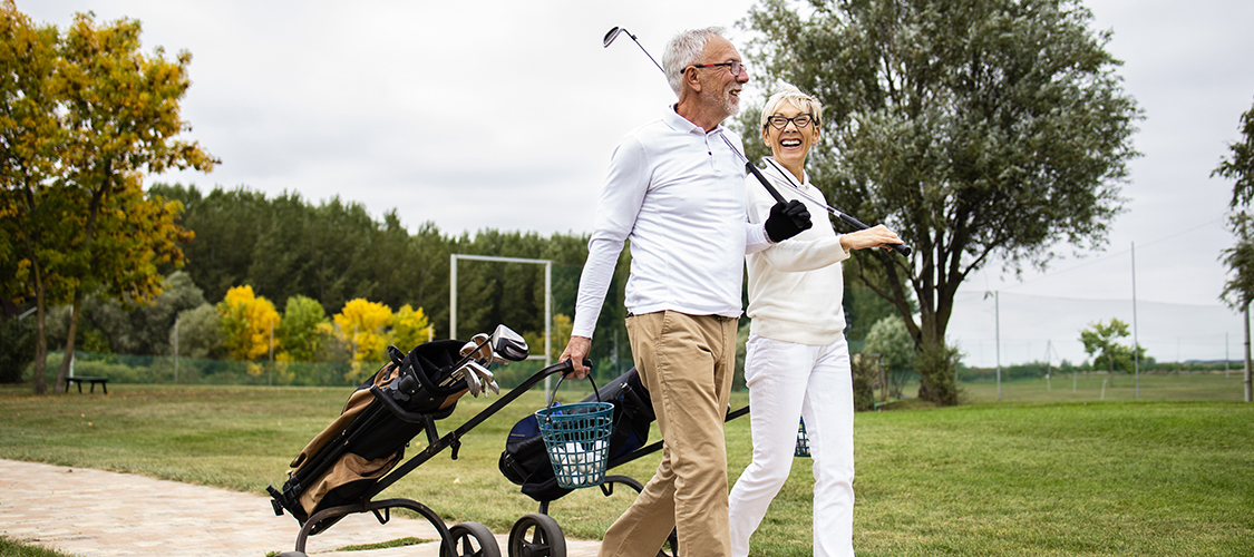A senior white woman and man play golf together