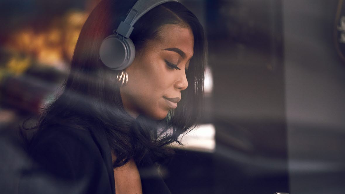 Kvinna med hörlurar hållandes i mobiltelefon