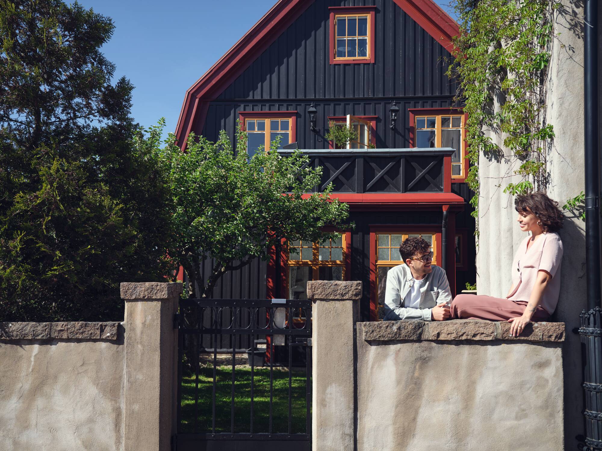 Två personer samtalar utanför en villa.