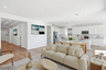 open-concept space with large neutral colored rug, off-white couch, and wooden coffee table