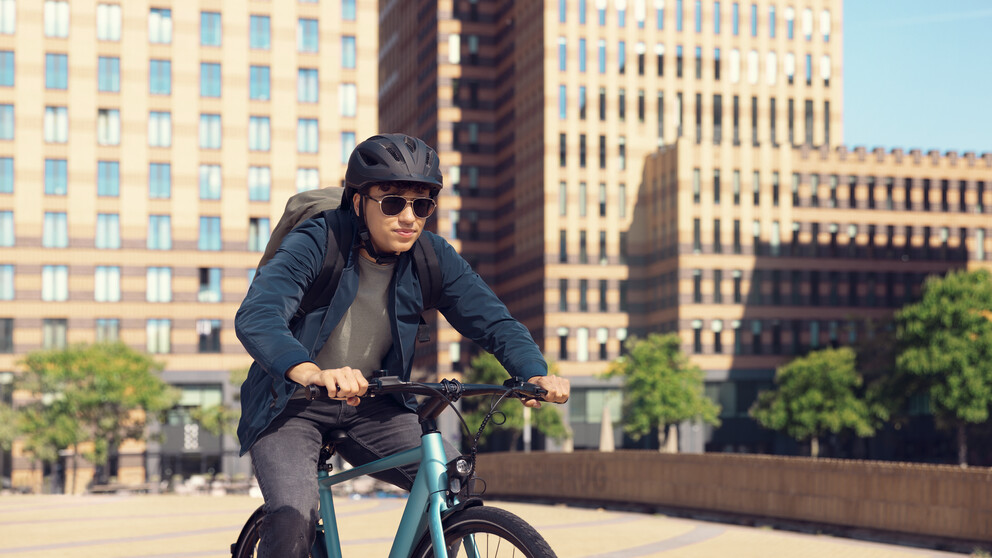 Man riding mountainbike in the city wearing helmet and HOYA Sensity Fast sunglasses
