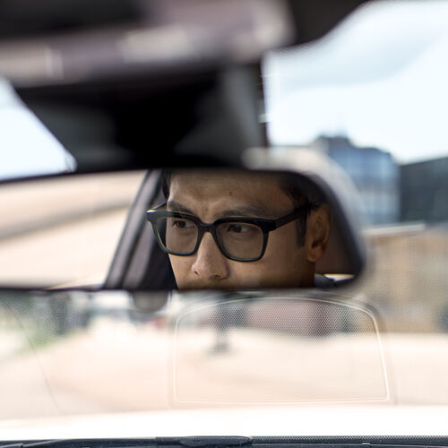 Hombre en el espejo retrovisor de un coche mientras lleva gafas de conducir